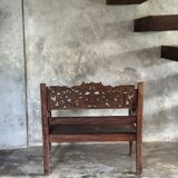 Small antique Indonesian bench in carved teak with plant and floral motifs.