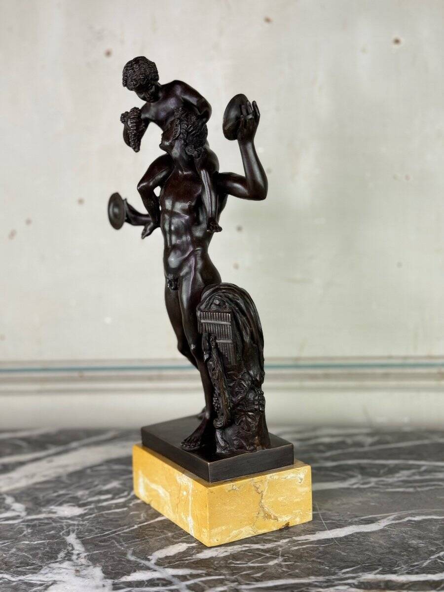 Dionysus on the shoulders of a satyr, bronze after the antique on a yellow Siena base.