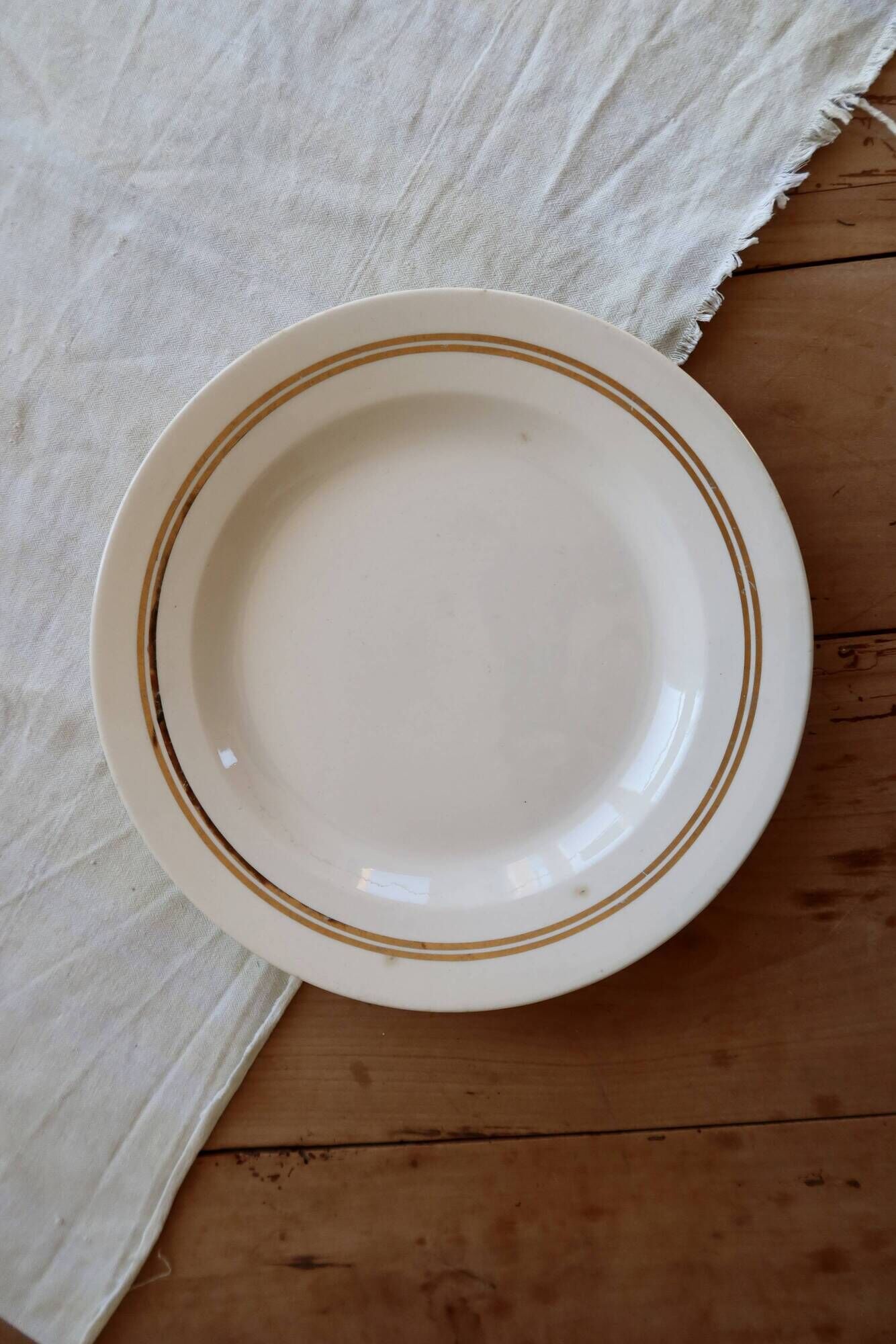 Round vintage ivory earthenware serving dish with double gold trim.