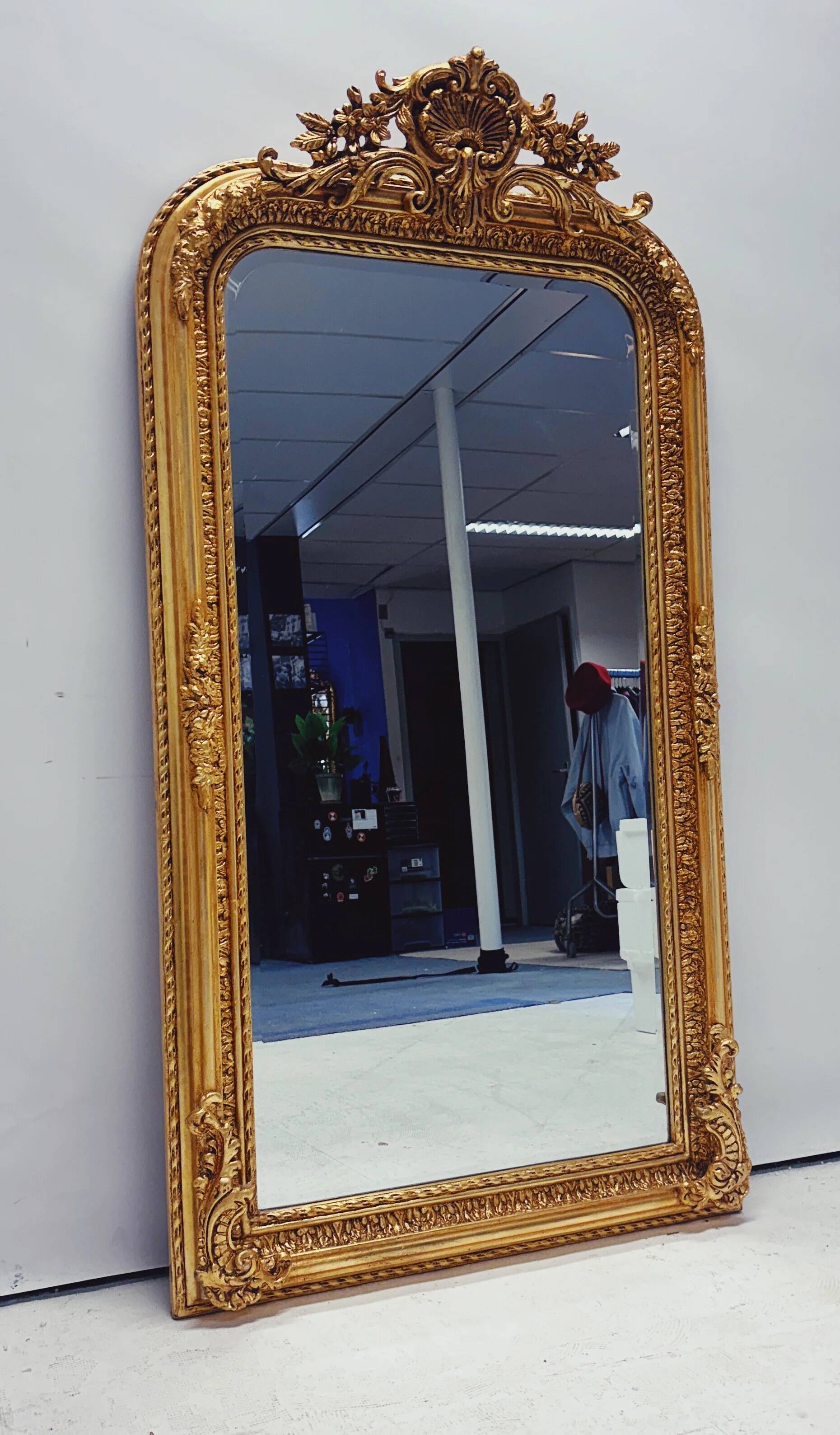 Grand miroir baroque en or avec un crête orné.