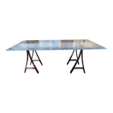 Vintage table with a glass top and smoked plastic trestle legs.