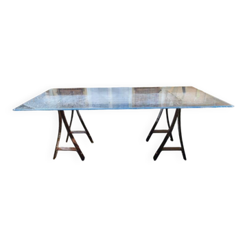 Vintage table with a glass top and smoked plastic trestle legs.