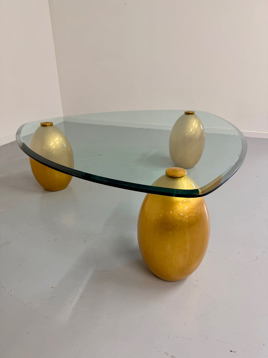 Vintage Italian design coffee table with a glass top and gold base, dating from the 1980s.