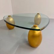 Vintage Italian design coffee table with a glass top and gold base, dating from the 1980s.