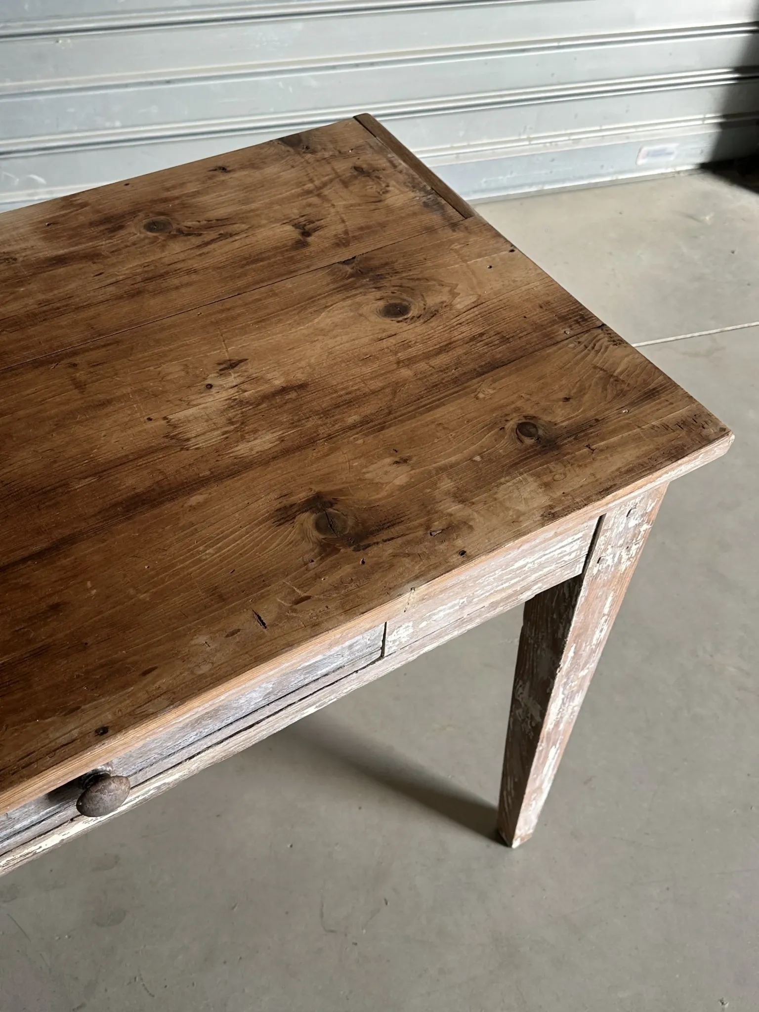 Vintage table made of raw wood with a distressed white base.