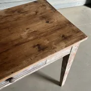 Vintage table made of raw wood with a distressed white base.
