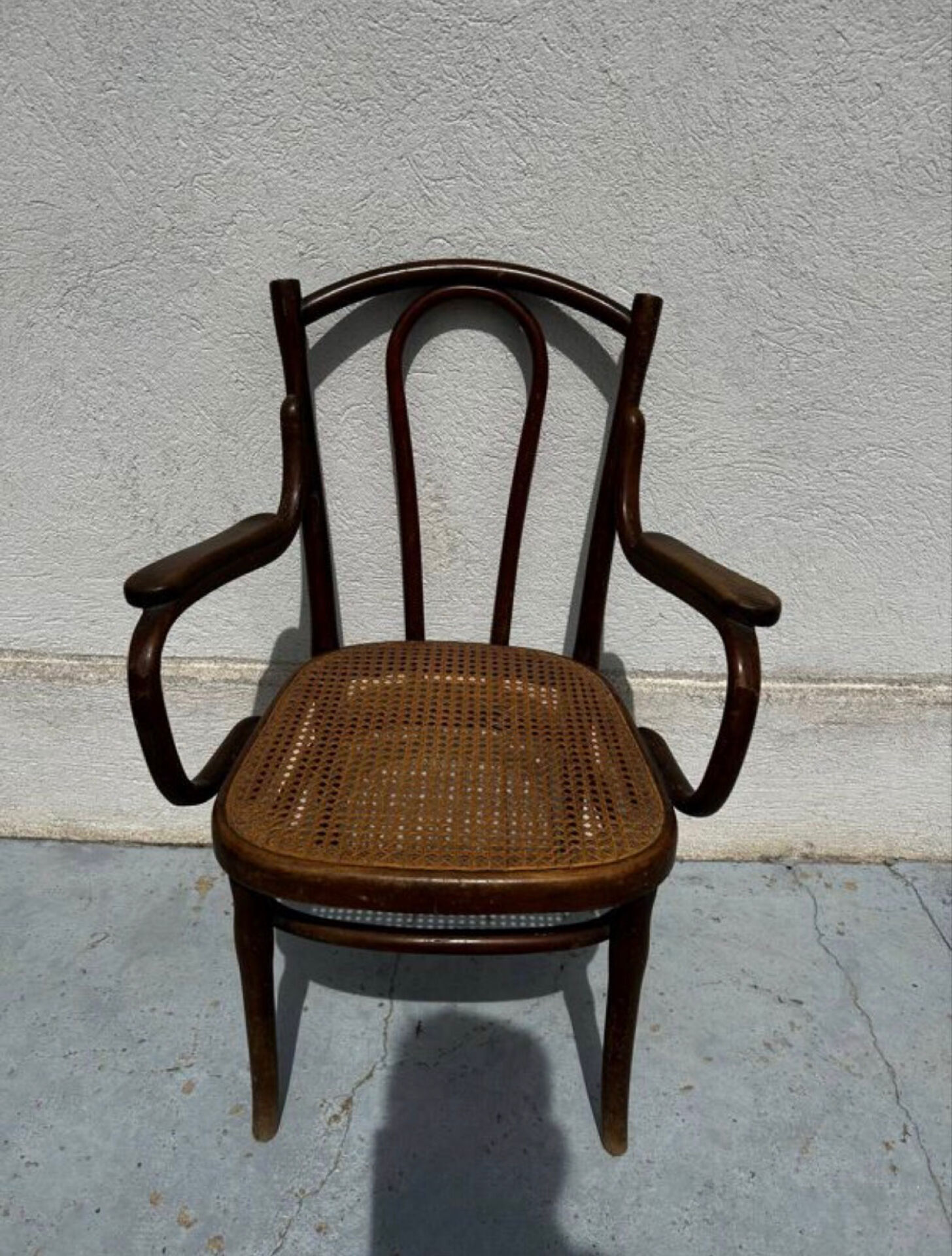 Thonet armchair stamped with curved wooden armrests and caning from the 19th century.
