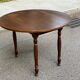 Round kitchen or dining table with extendable leaves in dark wood.