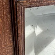 Antique mirror door (left) of a brown oak wardrobe with bevelled glass.