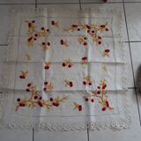 Square white doily. Embroidered with red tantrums. Lace entourage and days.