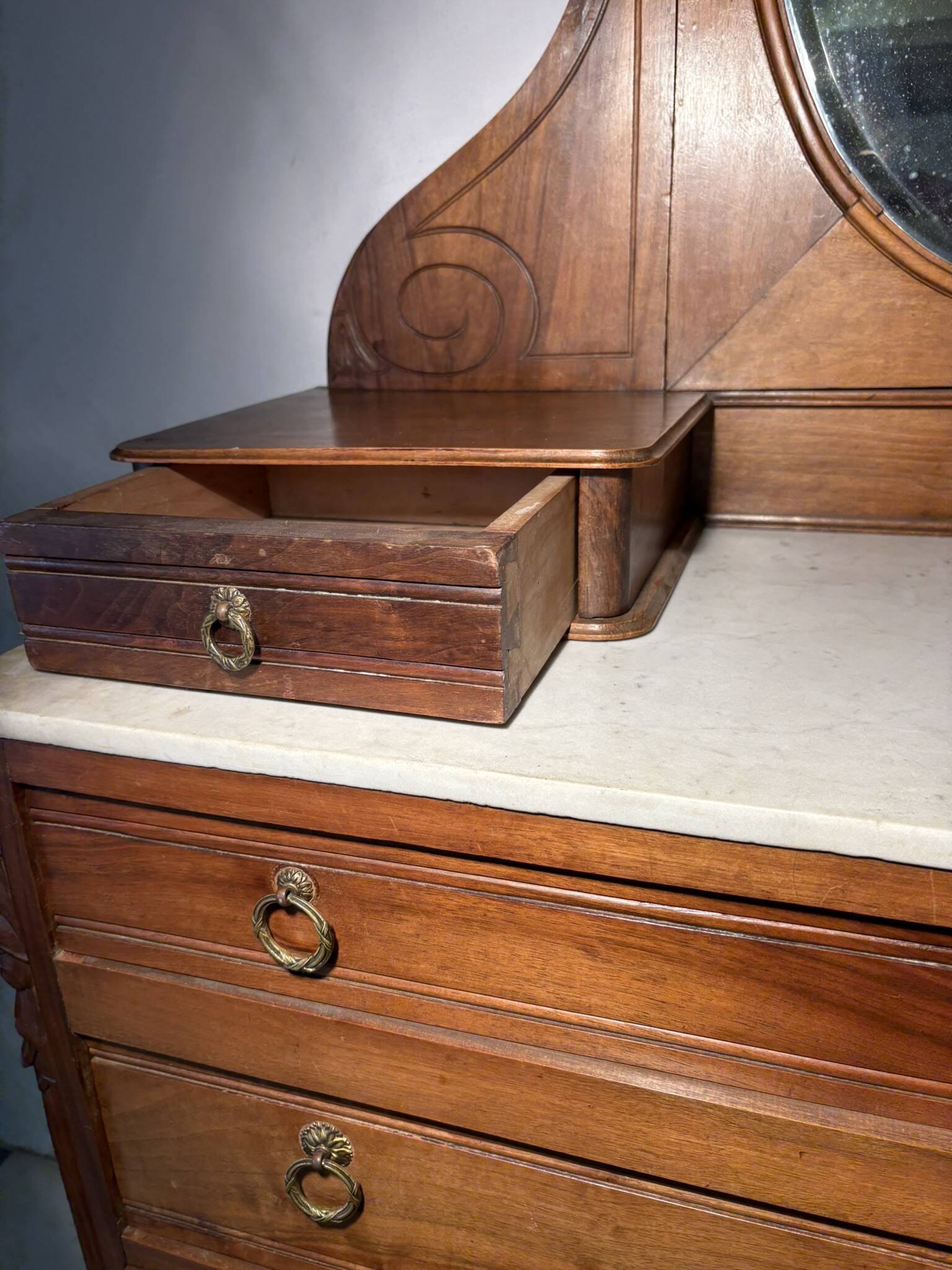 Antique carved wooden dressing table with marble and tilting oval mirror.
