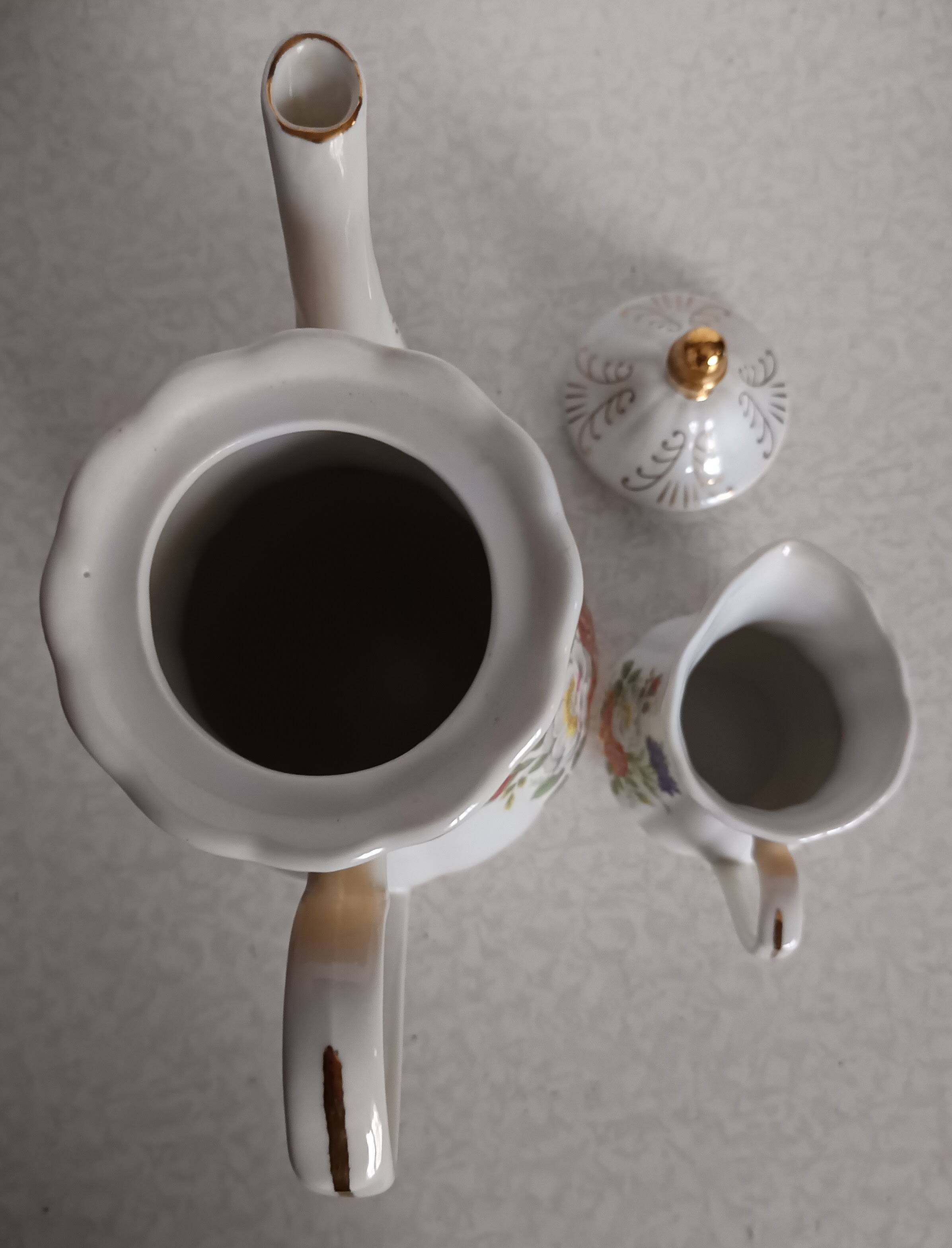 Golden porcelain teapot and coffee pot set with floral design and matching milk jug.