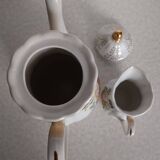 Golden porcelain teapot and coffee pot set with floral design and matching milk jug.