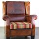 Very large worn sheepskin wing chair with a checked seat cushion