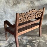 Small antique Indonesian bench in carved teak with plant and floral motifs.