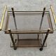 Mid Century Modern bar cart with 2 levels in brass and tinted glass.