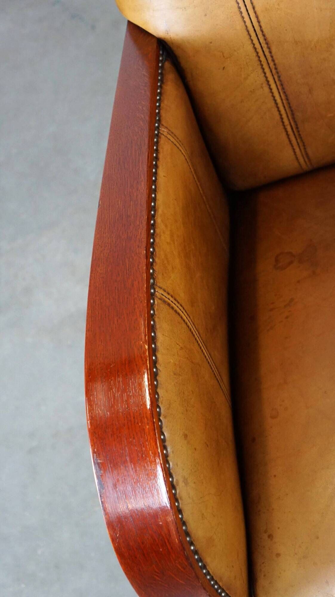 Luxurious cowhide Art Deco design armchair with wooden armrests and cognac-colored leather