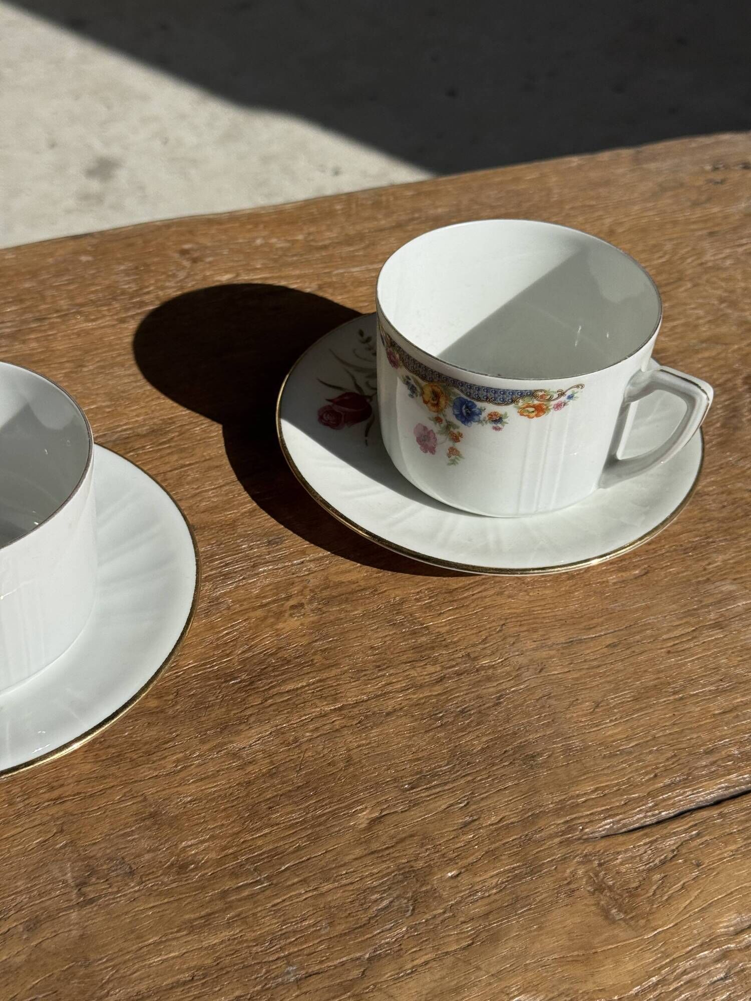 Pair of white porcelain cups from ADP France with a floral pattern and their s