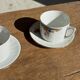 Pair of white porcelain cups from ADP France with a floral pattern and their s