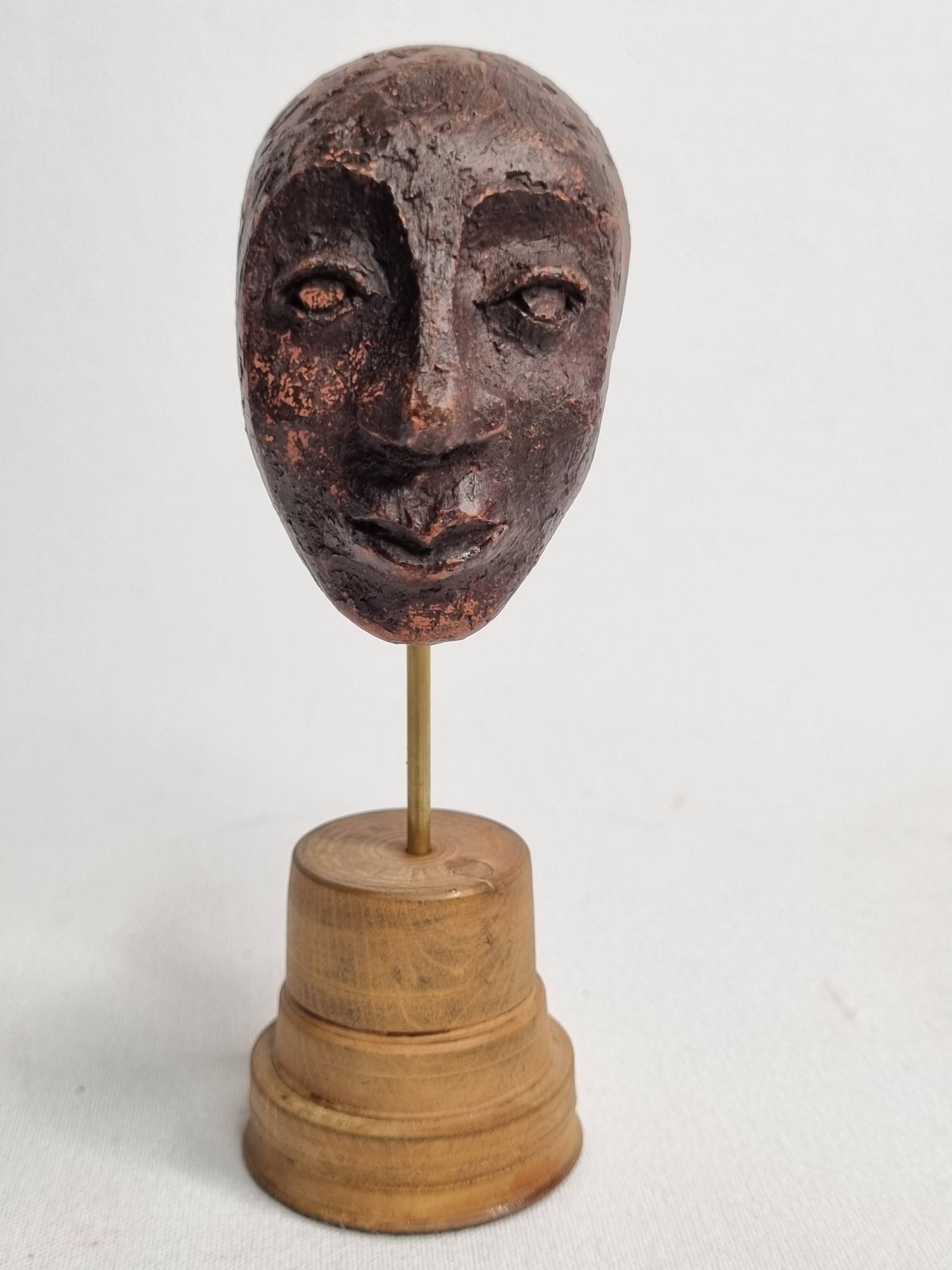 Expressive sculpted head in patinated terracotta on wooden base, 14 cm