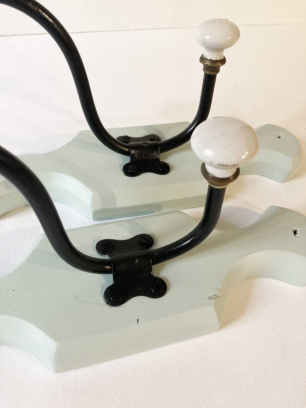 Antique metal and porcelain coat hooks, painted wooden support
