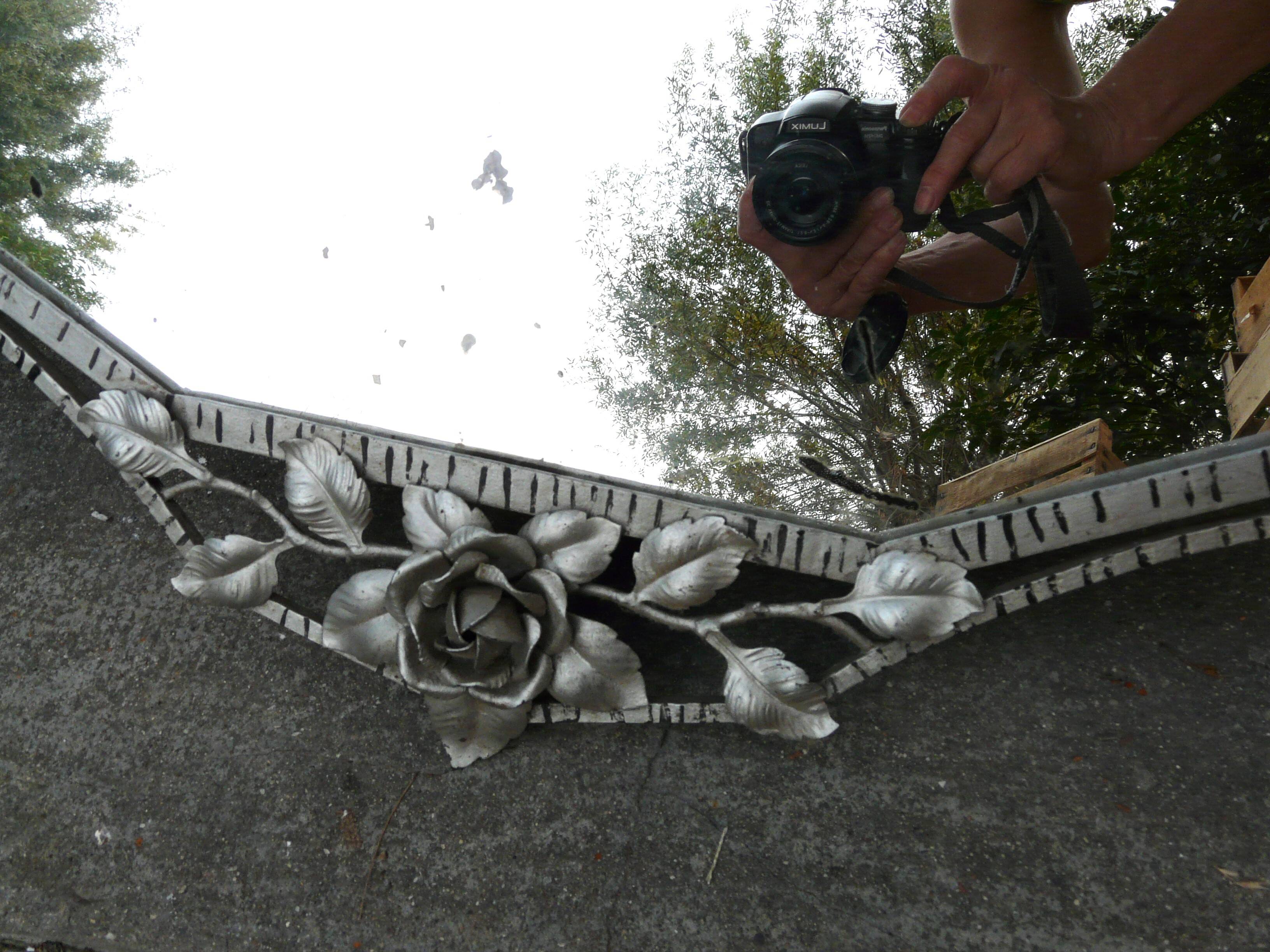 Beveled mirror with art-deco wrought iron frame and floral decor with hanging chain