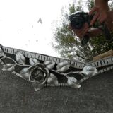 Beveled mirror with art-deco wrought iron frame and floral decor with hanging chain