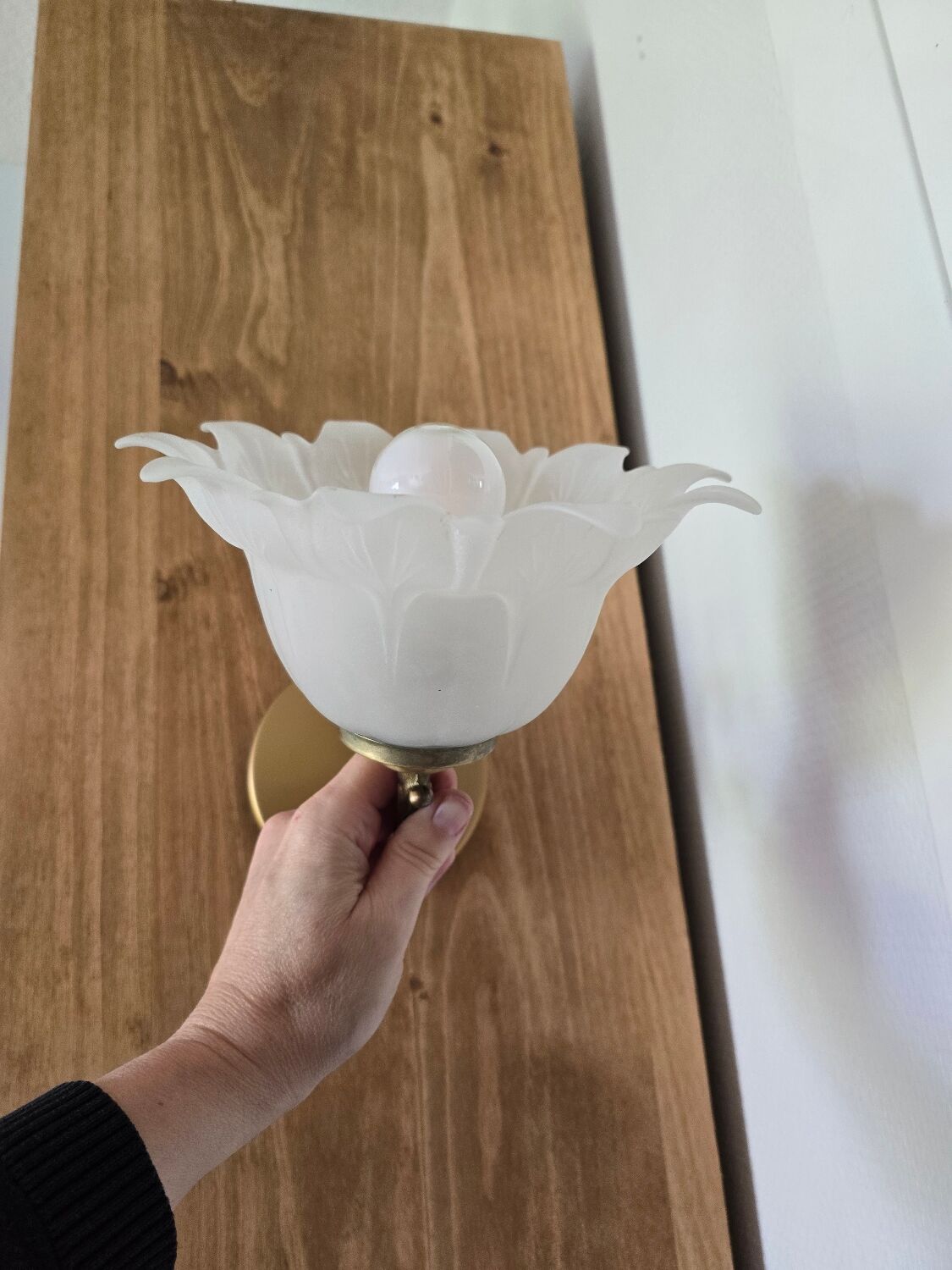 Frosted glass tulip wall sconces with brass arms.