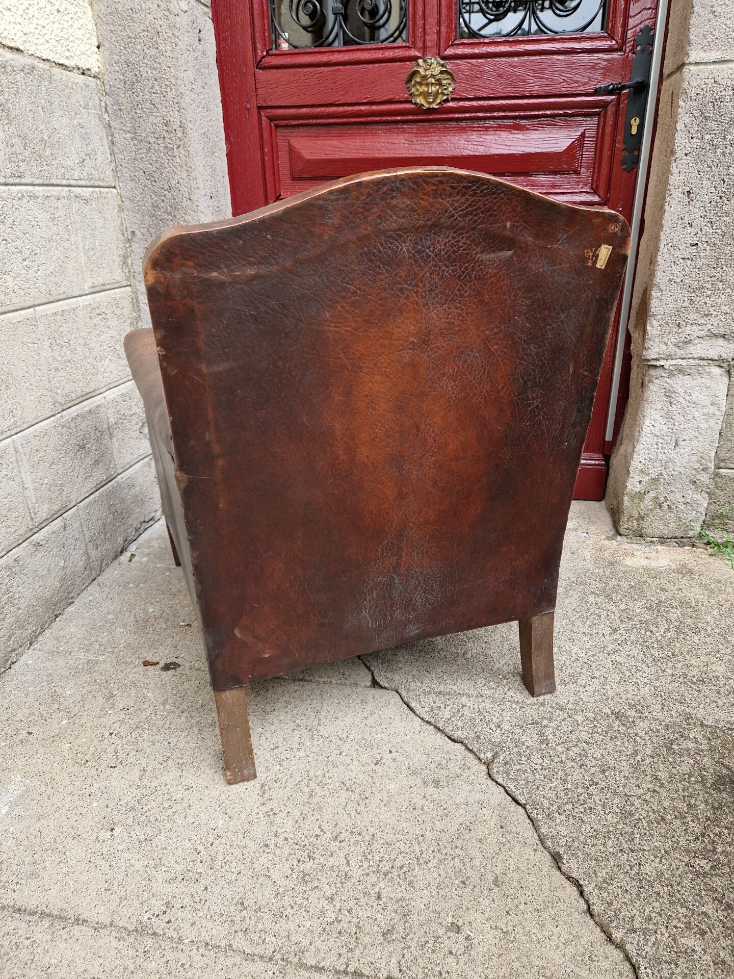 Antique club chair in patinated brown leather, early 20th century English style.