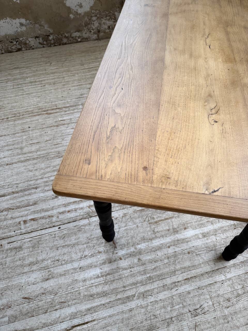 Oak farmhouse table with turned black legs.