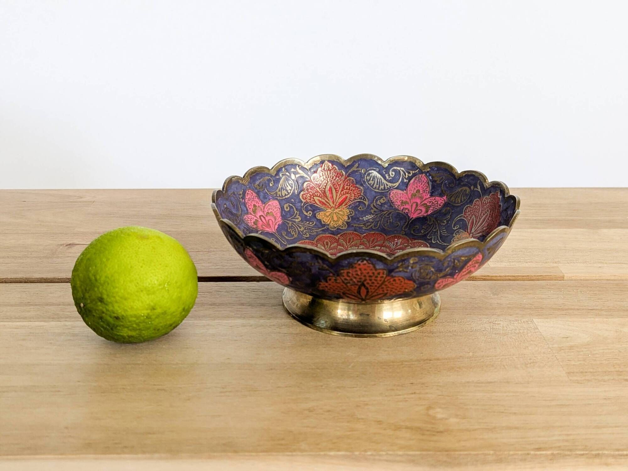 Vintage brass bowl with peacock motif, painted enamel, scalloped edge on a pedestal.