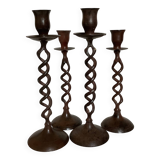 Four twisted metal candle holders with a rusty appearance