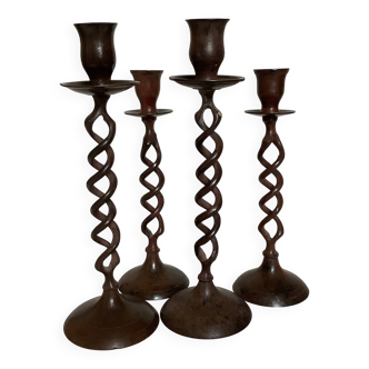 Four twisted metal candle holders with a rusty appearance