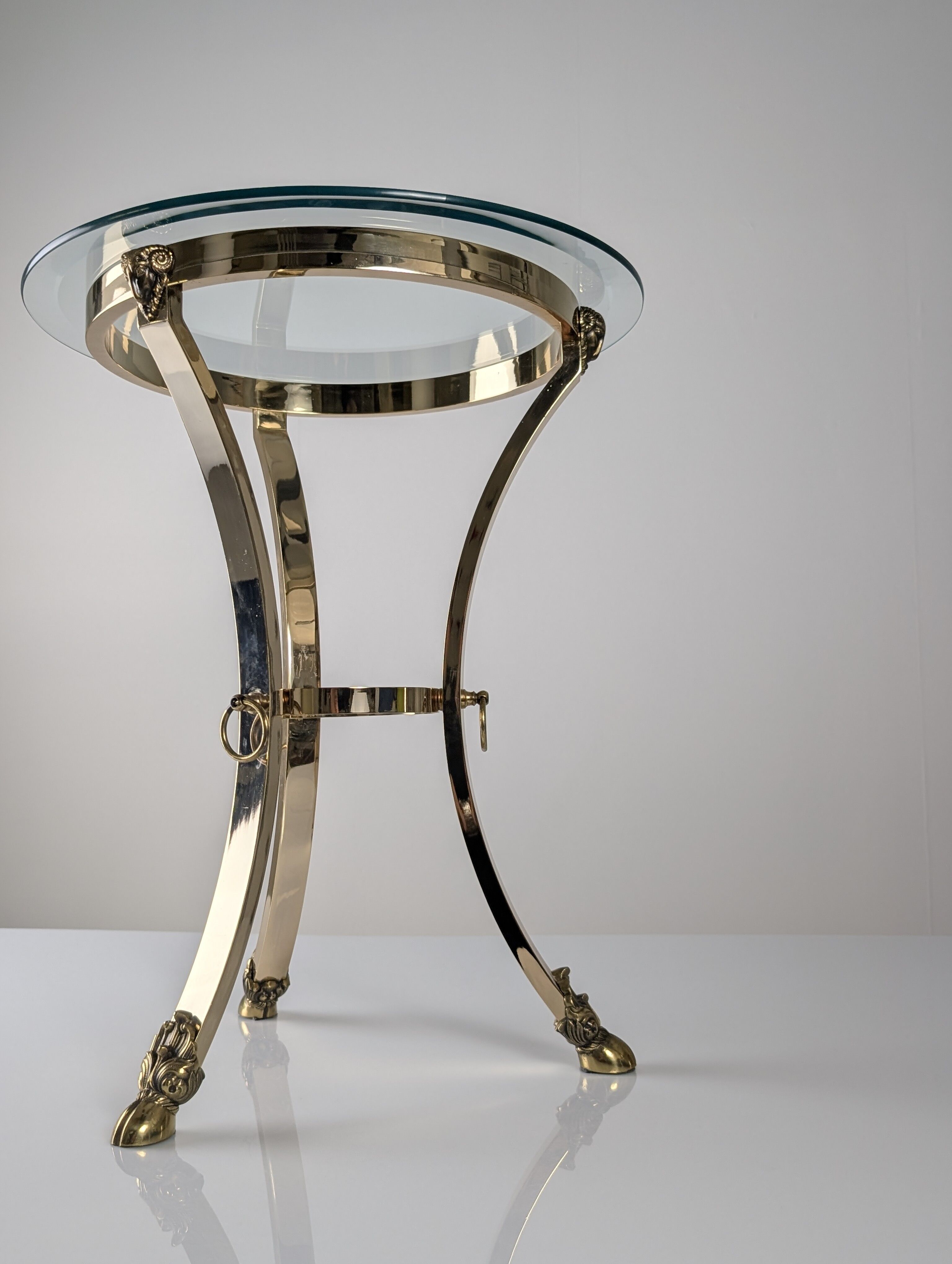 Neoclassical side table in brass and bevelled glass with ram's heads, 1970s.