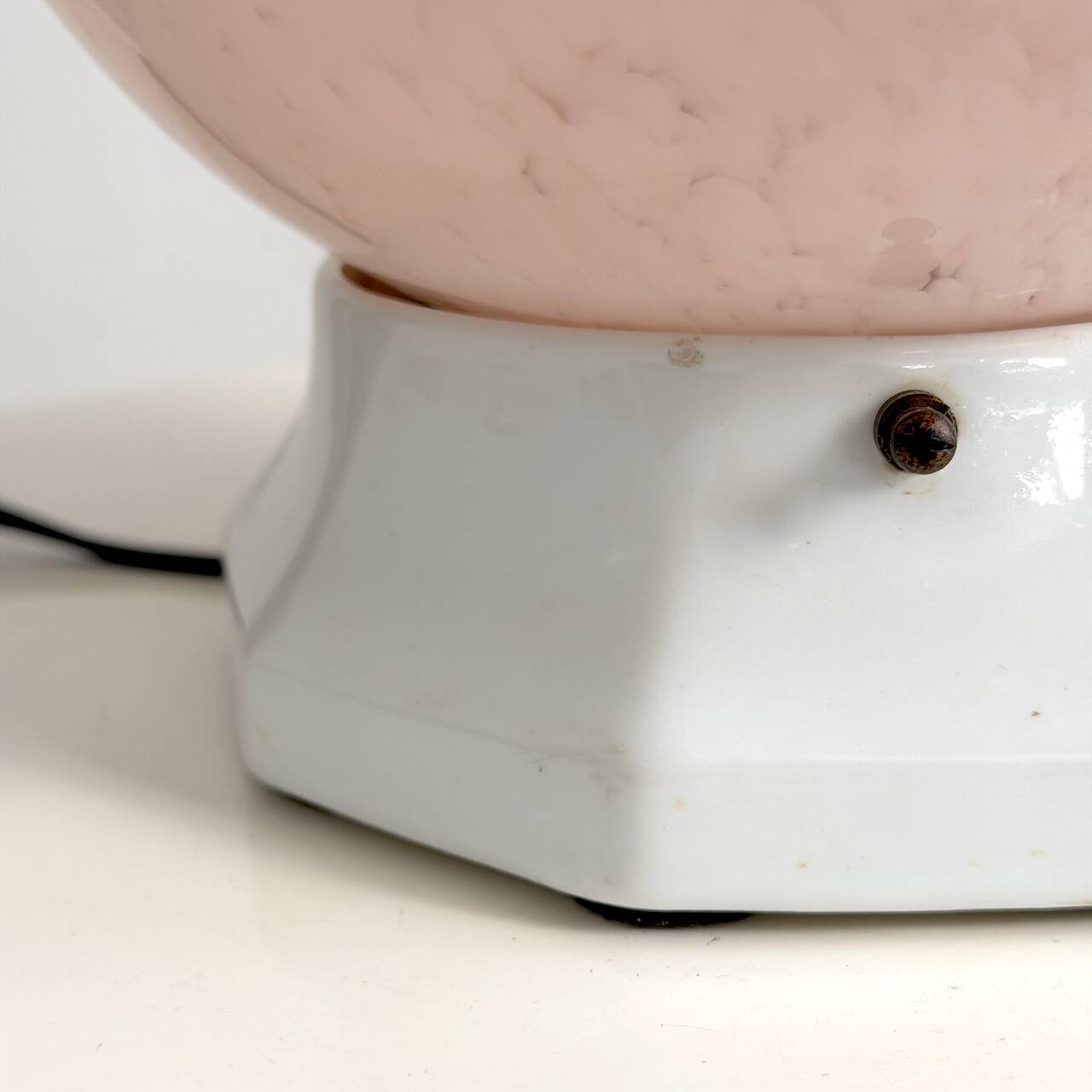 Art Deco lamp with a speckled pink glass globe and a white ceramic base.