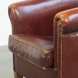 Comfortable, rugged cognac-colored sheepskin club armchair with a characteristic seat cushion