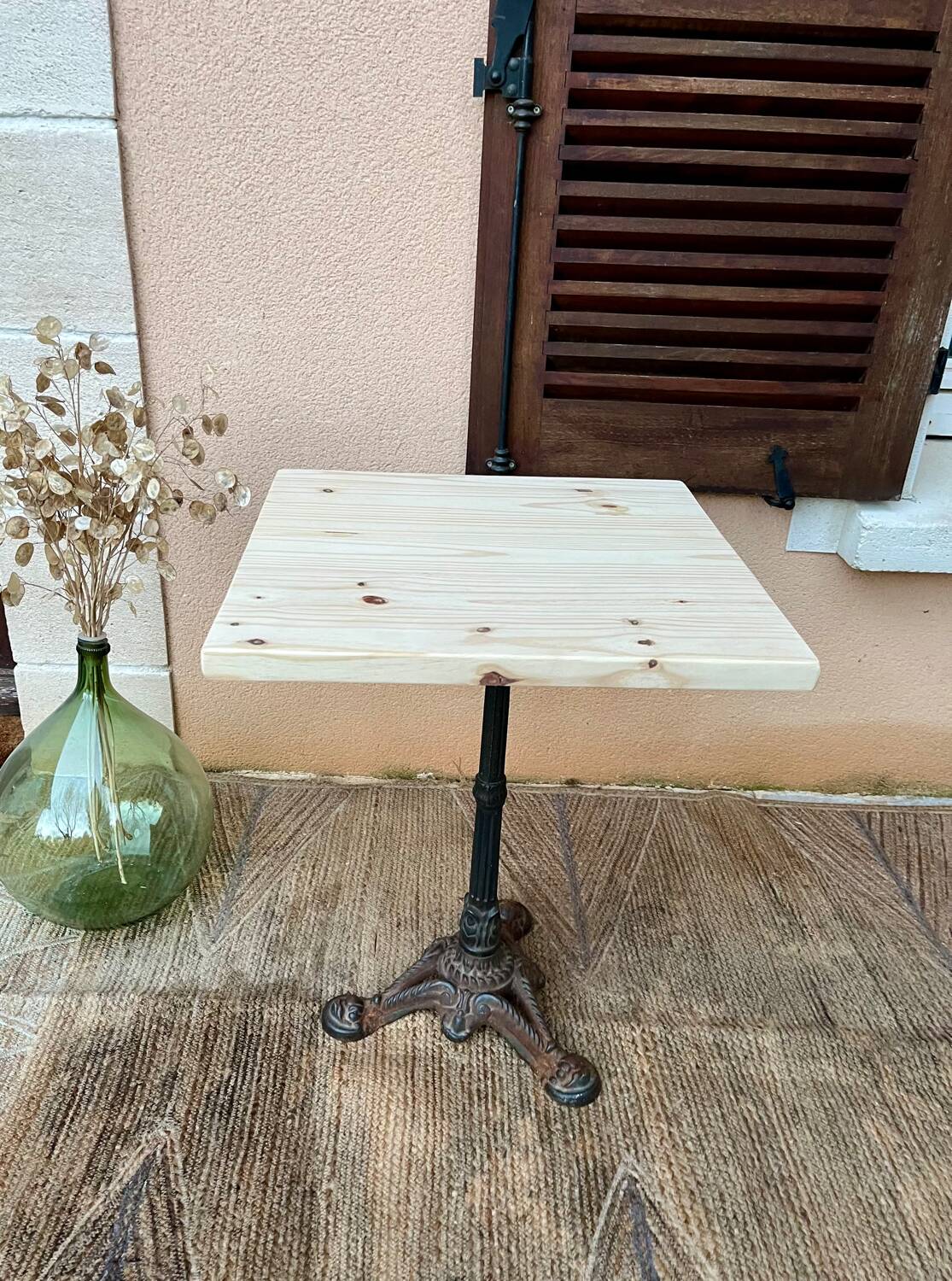 Bistro table with a raw wood top and a central cast iron base.