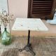 Bistro table with a raw wood top and a central cast iron base.