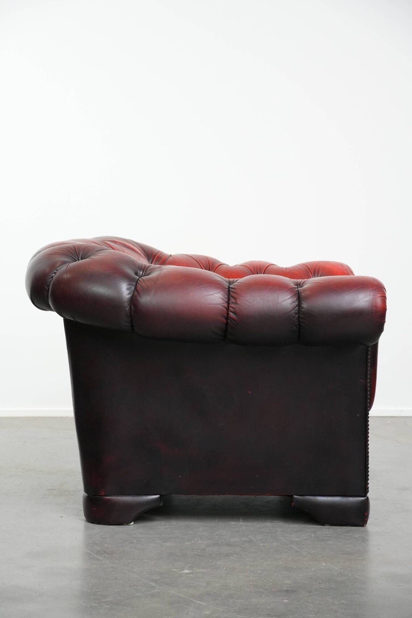 Classic cowhide chesterfield buttonseat armchair in a beautiful red colour and elegant round shapes