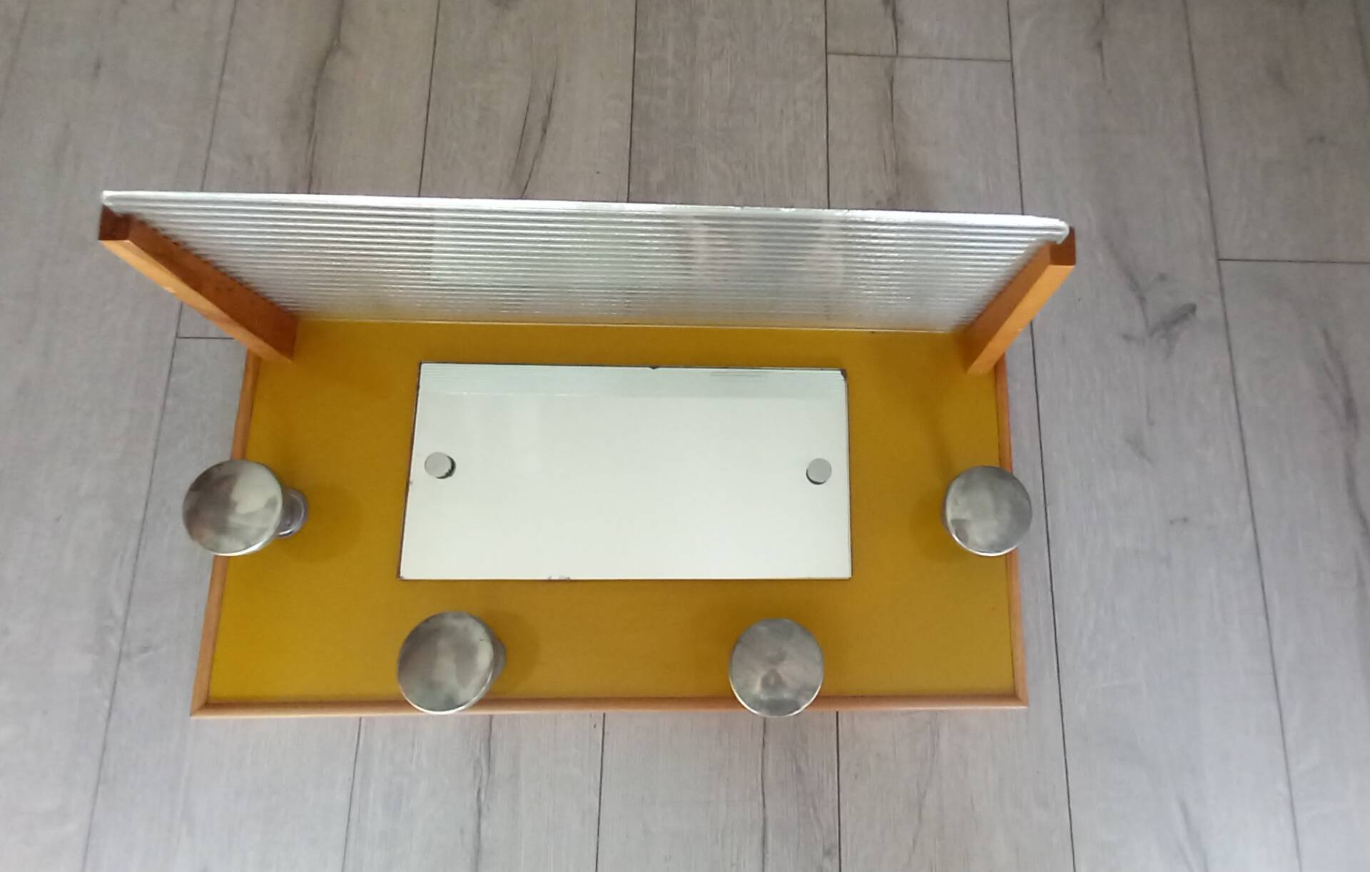 1950s coat rack with mirror, metal hooks, and glass shelf.