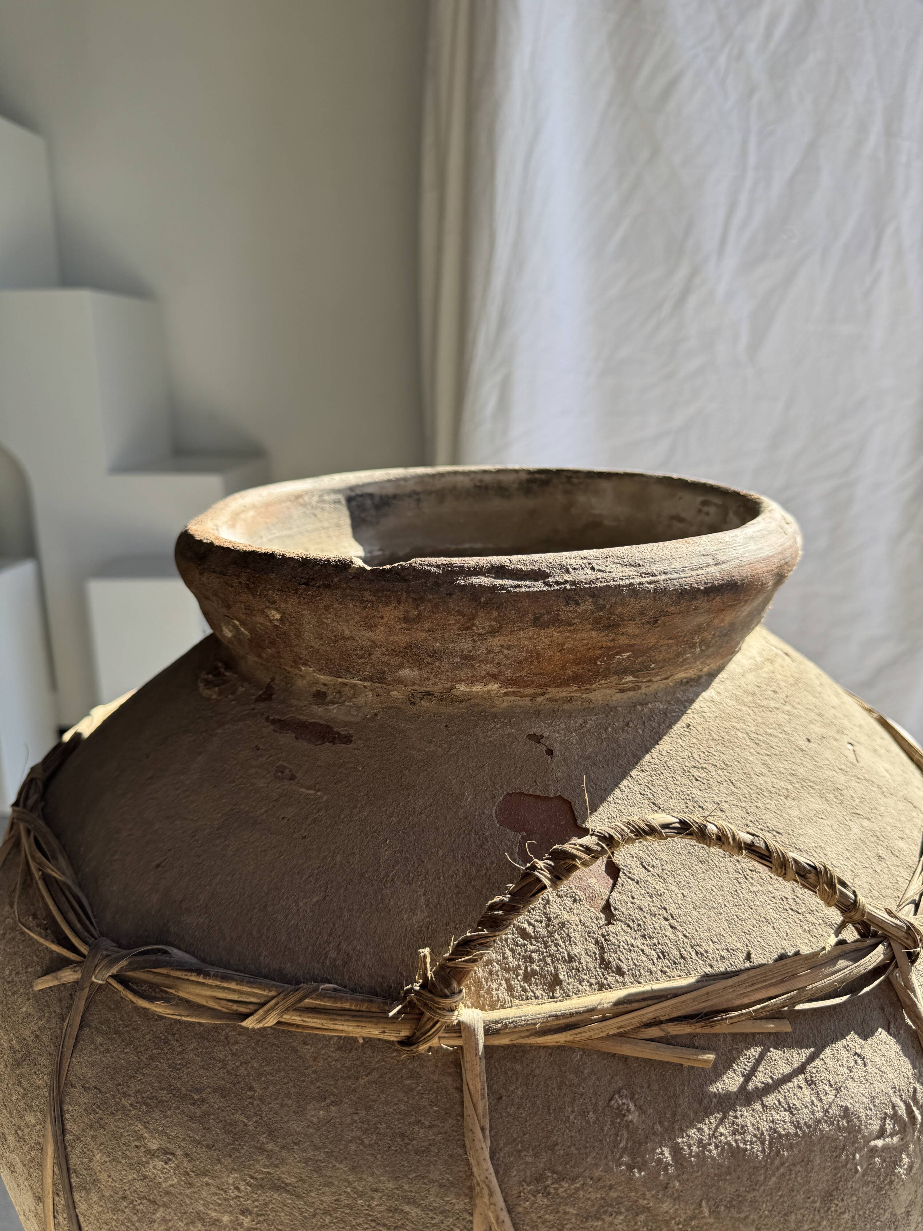 Very large grey and red terracotta pot with handles and rattan crossbars.