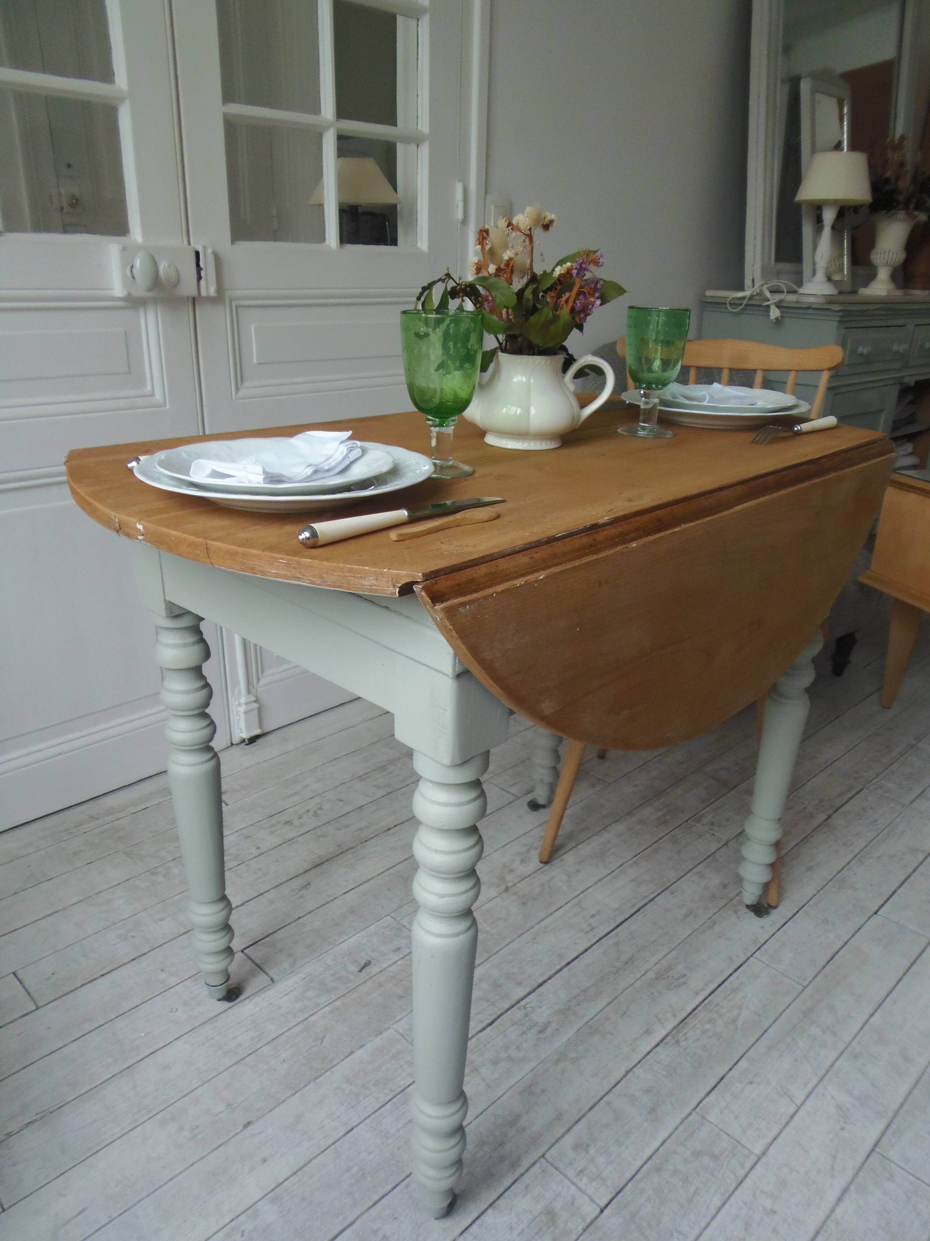 Raised walnut table with drop-leaf top, base on verdigris castors.