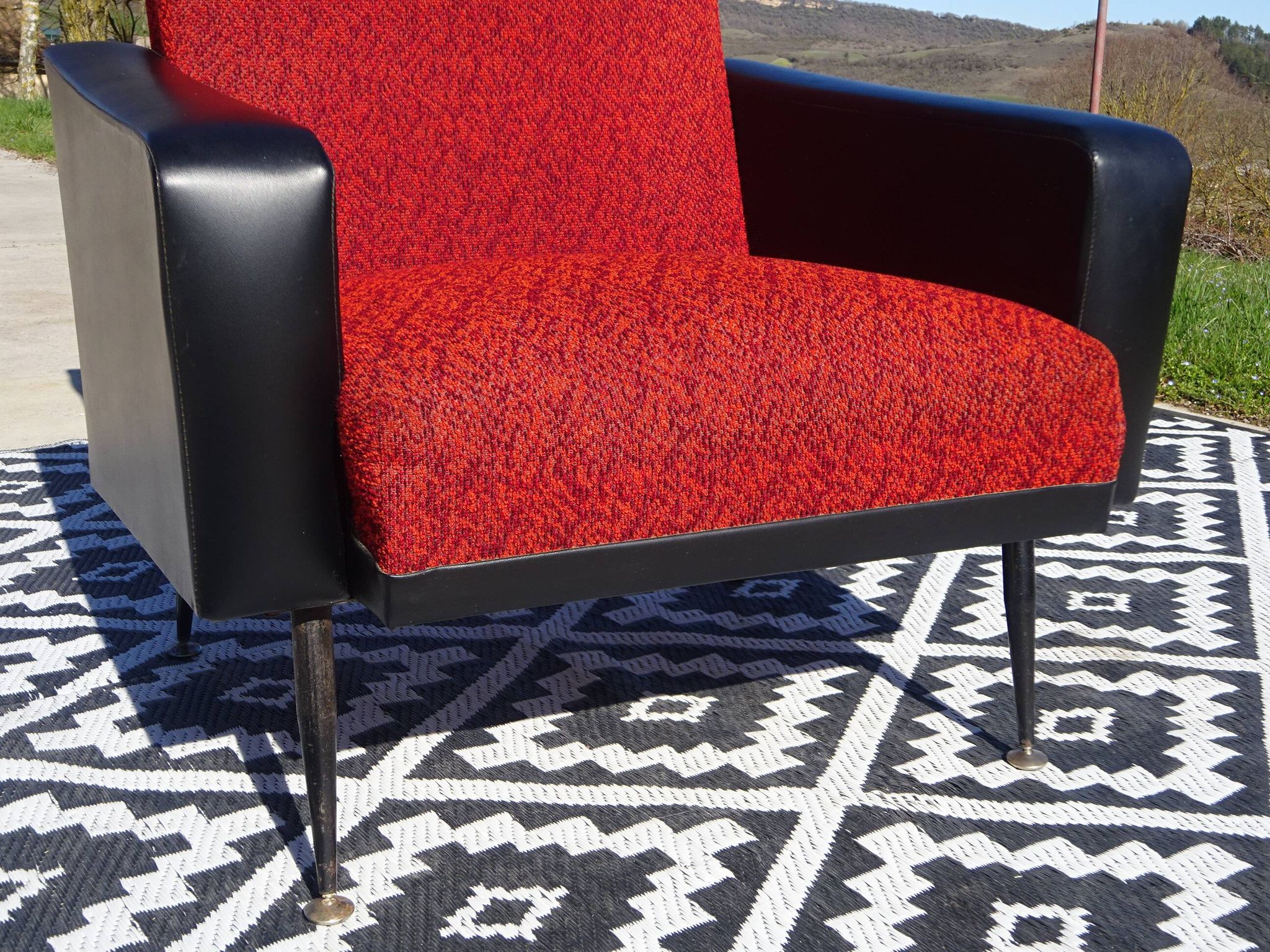 Pair of vintage armchairs in black faux leather and red fabric.