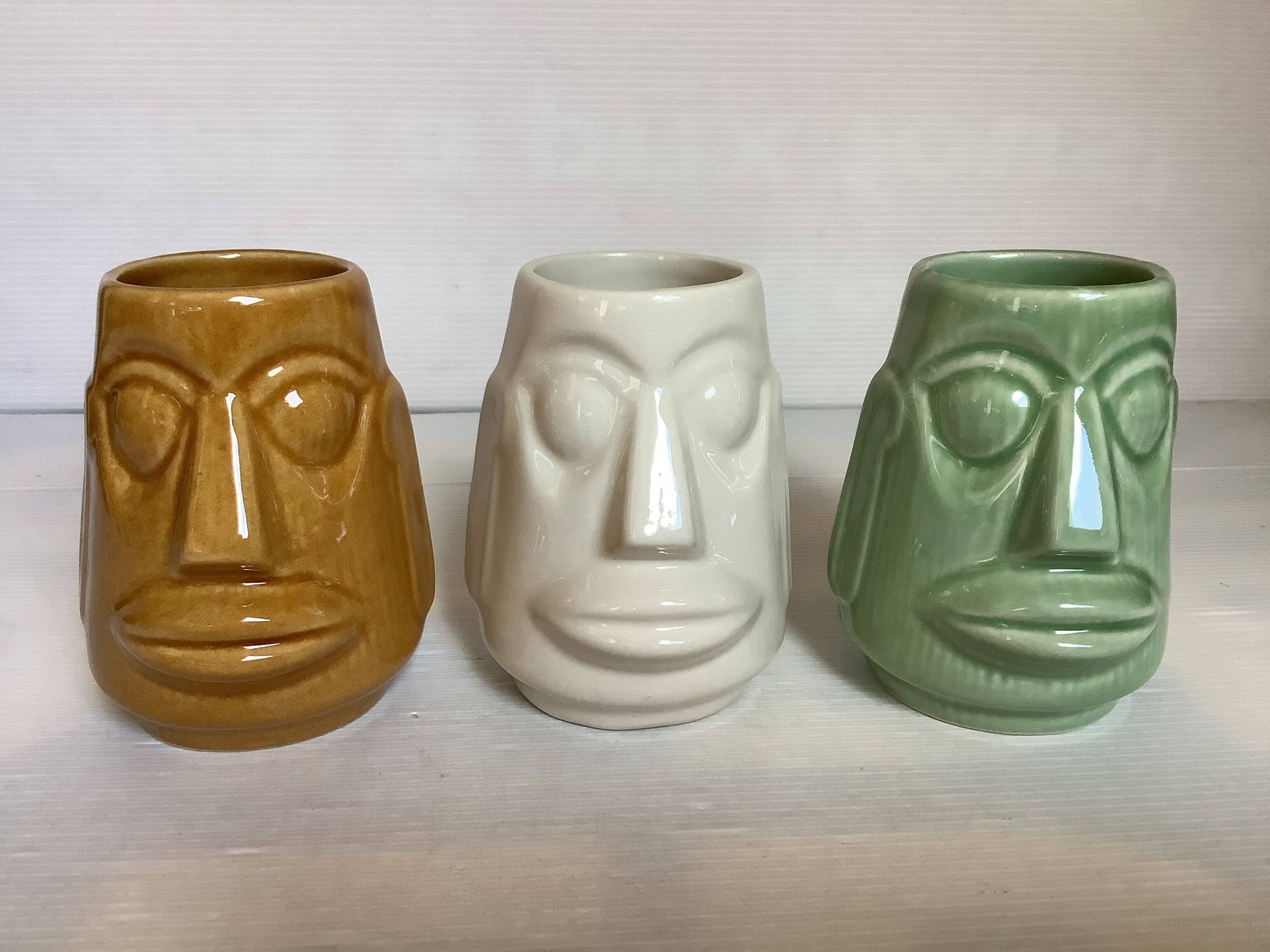 Set of three small Moai-style head vases.