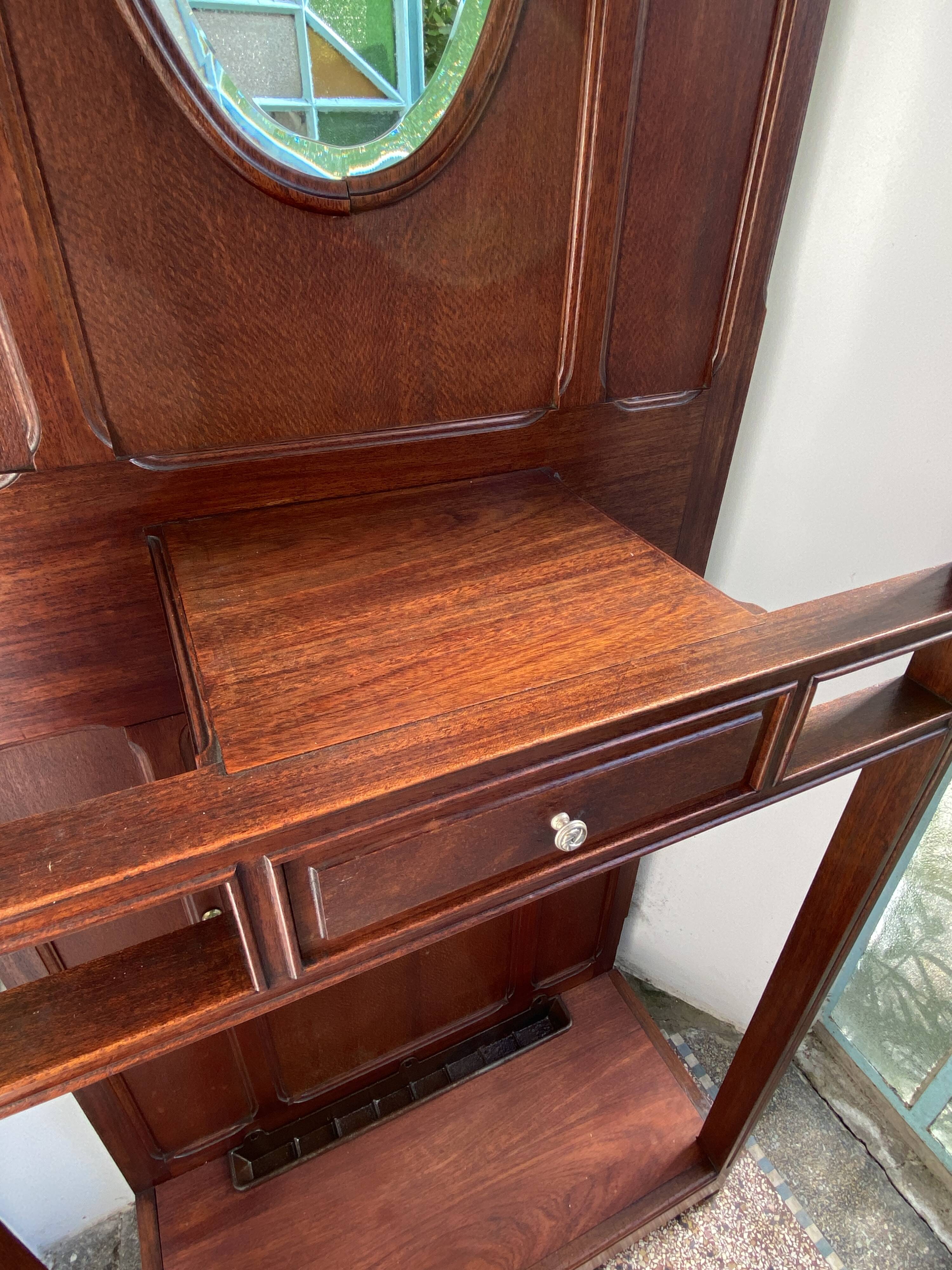 Antique wooden coat rack with mirror and shelf.