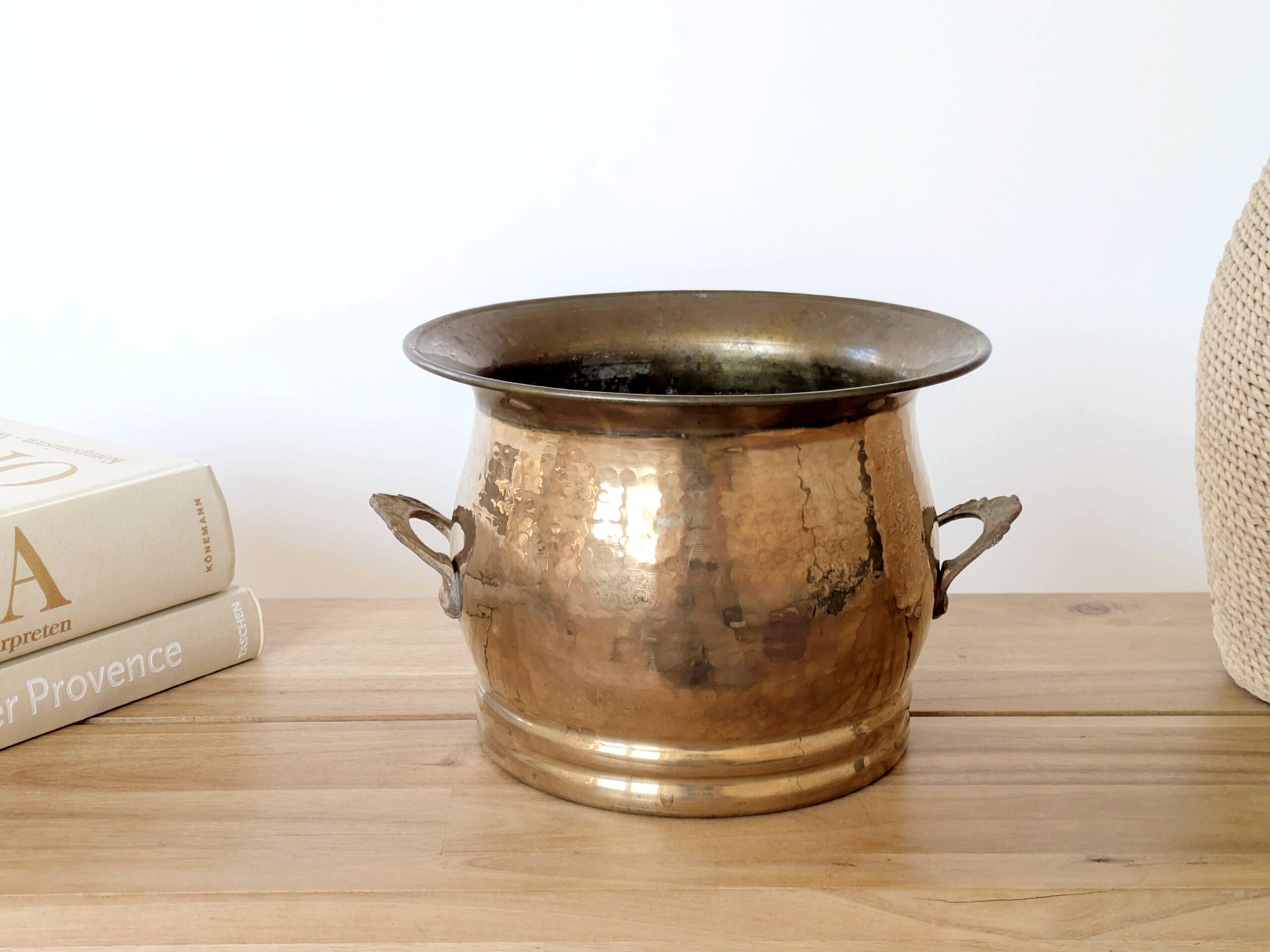 Vintage round cache-pot in hammered brass with decorative handles and patina.