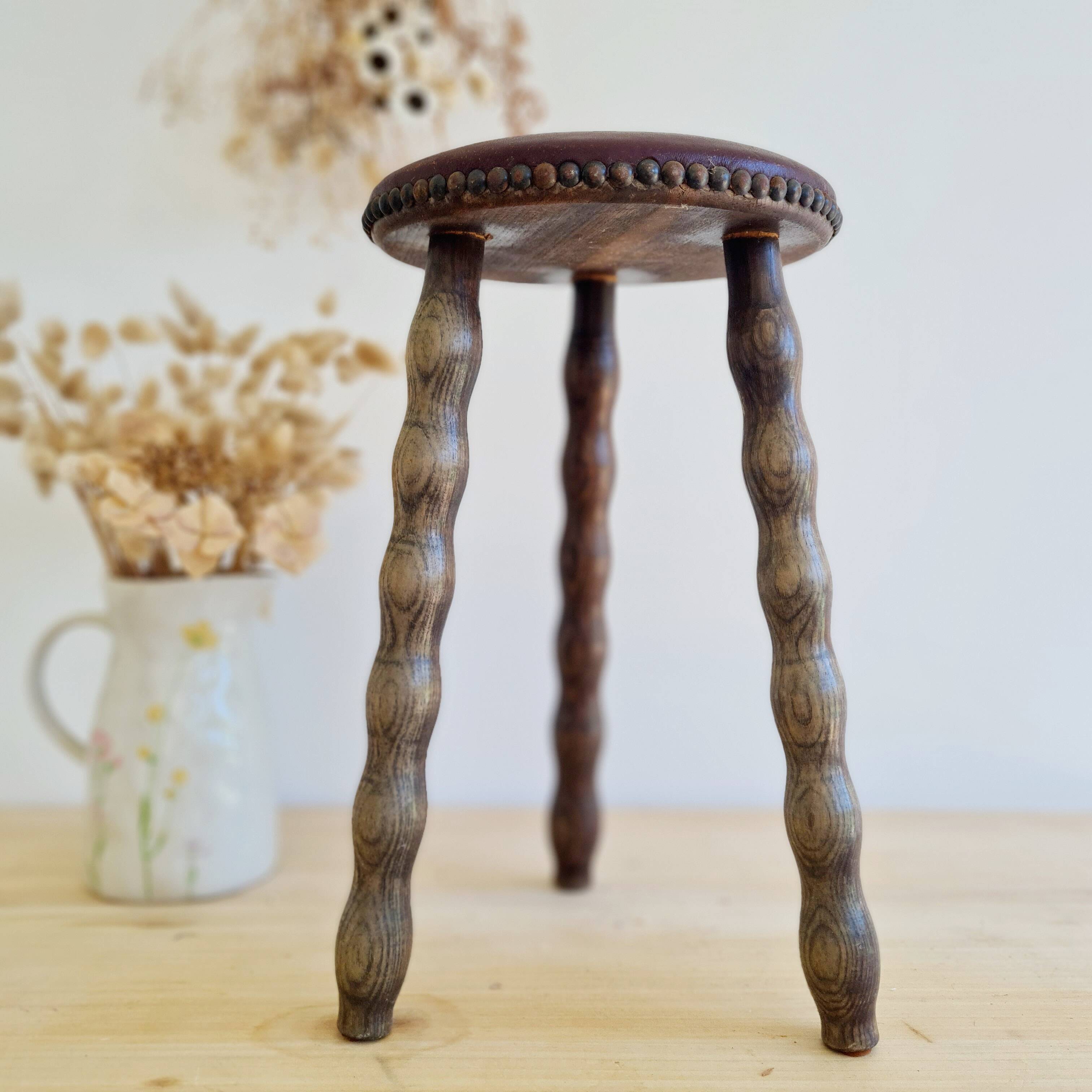 Antique tripod stool with turned wooden legs and leather seat.