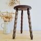 Antique tripod stool with turned wooden legs and leather seat.