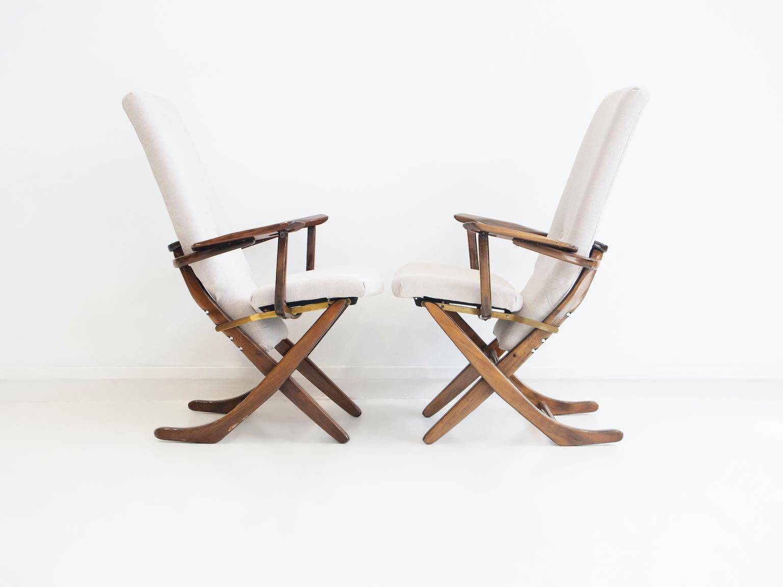 Pair of varnished wooden reclining armchairs, upholstered in lightweight fabric.