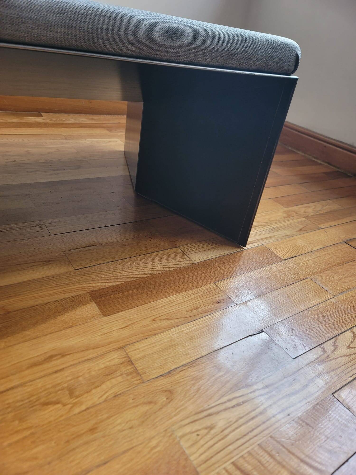 Minimalist/industrial coffee table with a black metal frame and a grey fabric top.